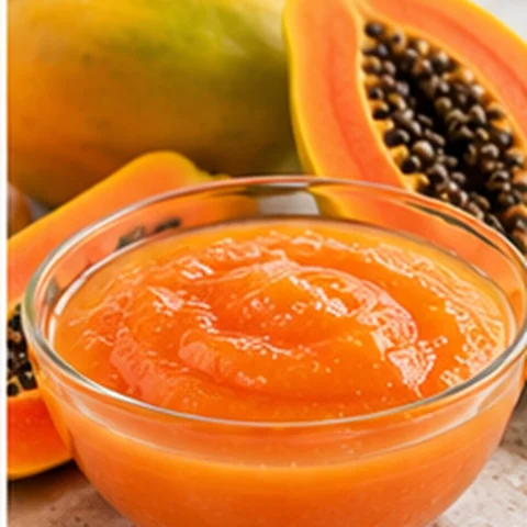 Orange papaya purée in a bowl with fresh papaya